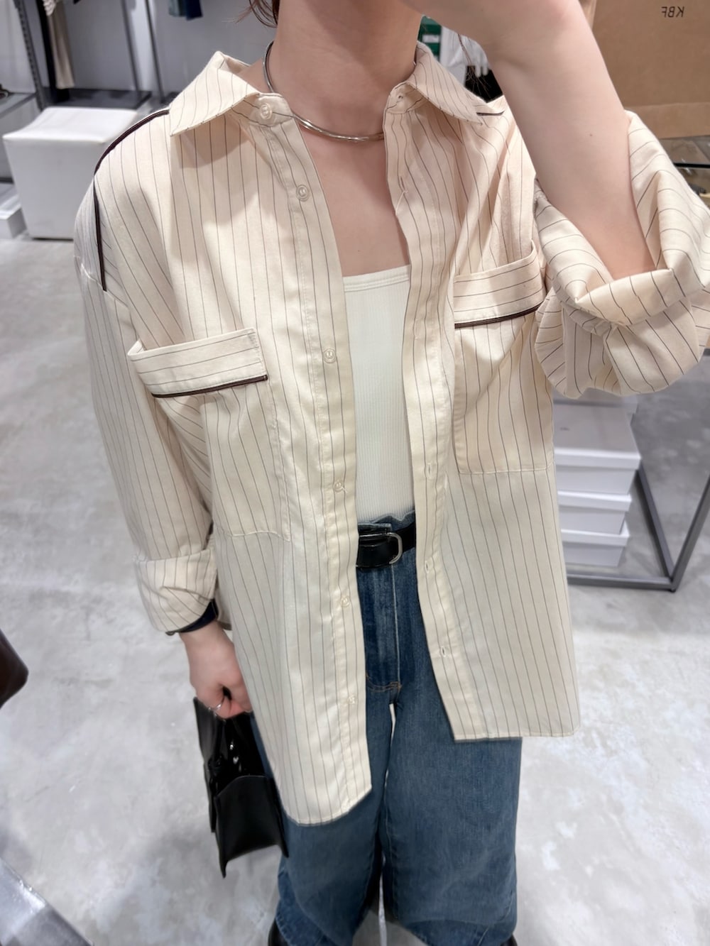 ブルー系のデニムパンツ、ブラック系のハンドバッグ、ホワイト系のキャミソールを着用したレディースの春コーディネートの5枚目の写真