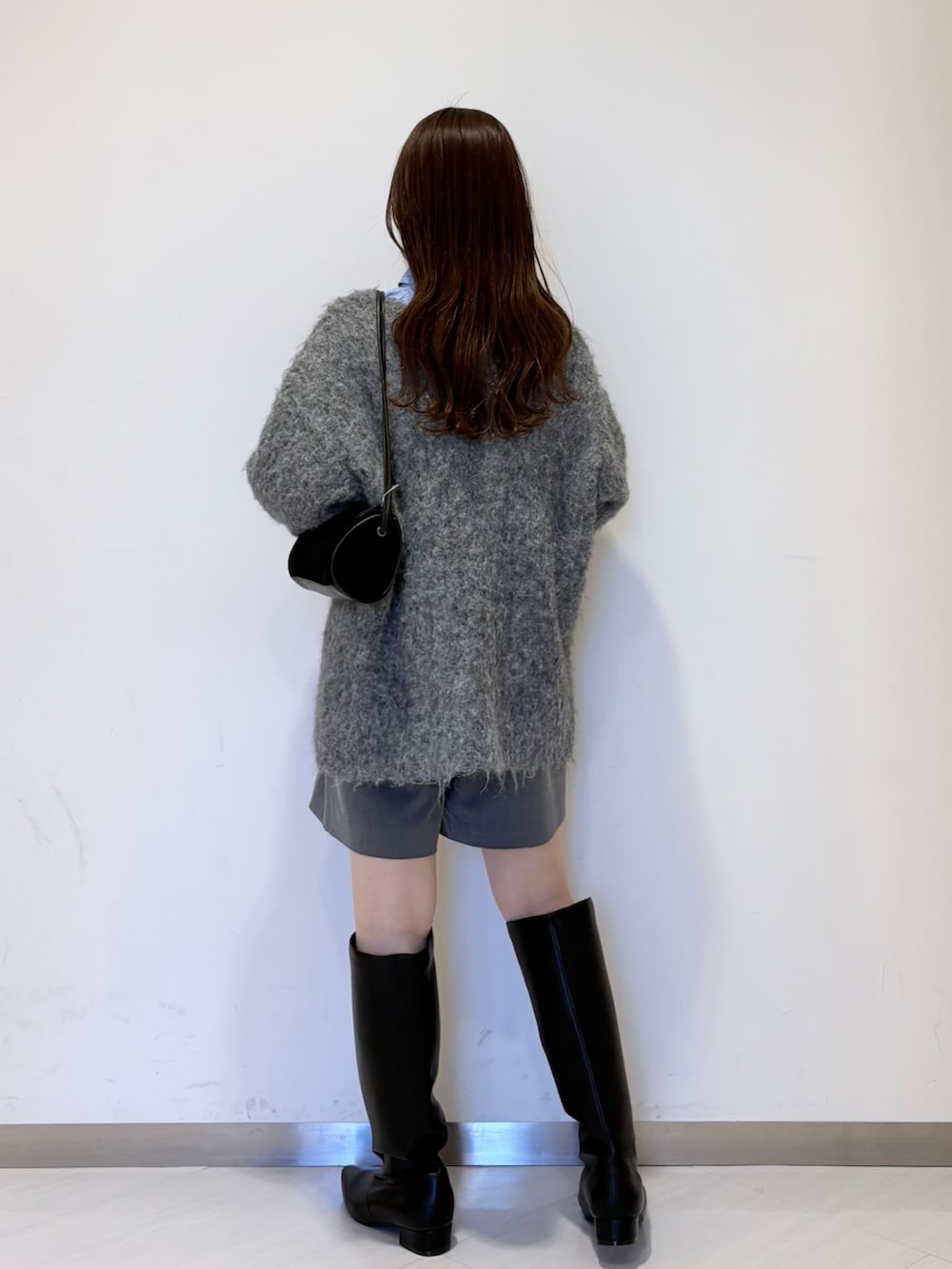 ブルー系のシャツ/ブラウス、グレー系のニット/セーター、ブラック系のショルダーバッグを着用したレディースの冬コーディネートの4枚目の写真