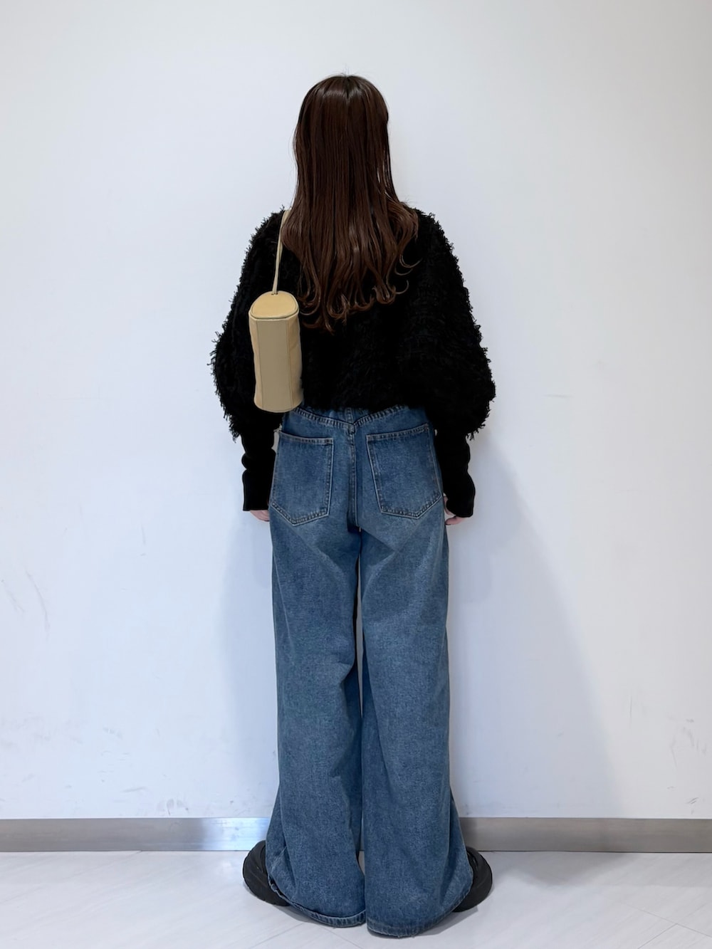 ブラック系のカーディガン/ボレロ、グレー系のTシャツ/カットソー、ブルー系のデニムパンツを着用したレディースの冬コーディネートの3枚目の写真