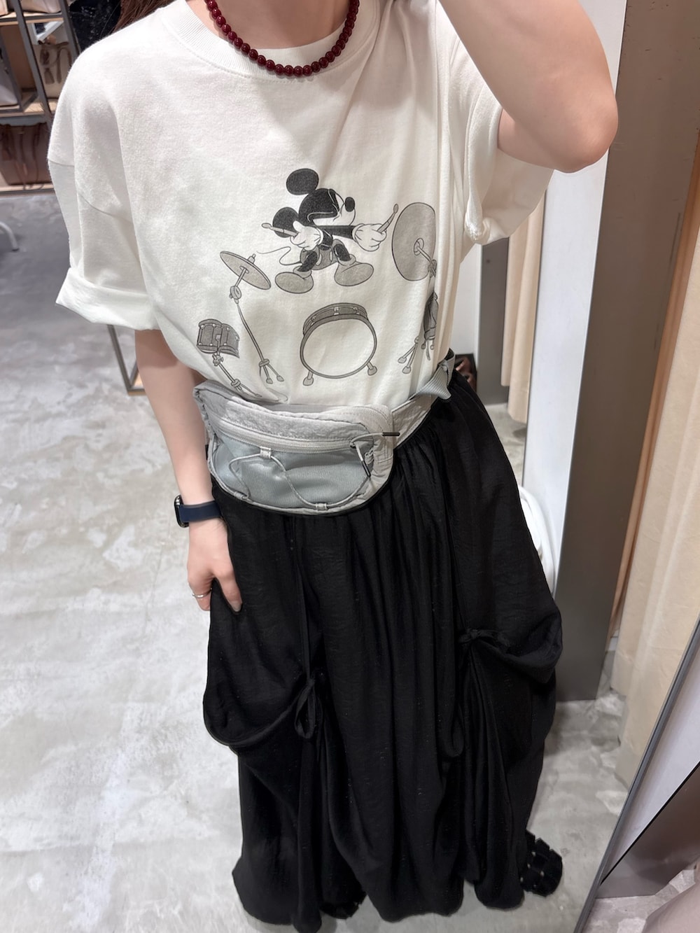 ホワイト系のTシャツ/カットソー、ブラック系のスカート、グレー系のボディバッグ/ウエストポーチを着用したレディースの春コーディネートの5枚目の写真