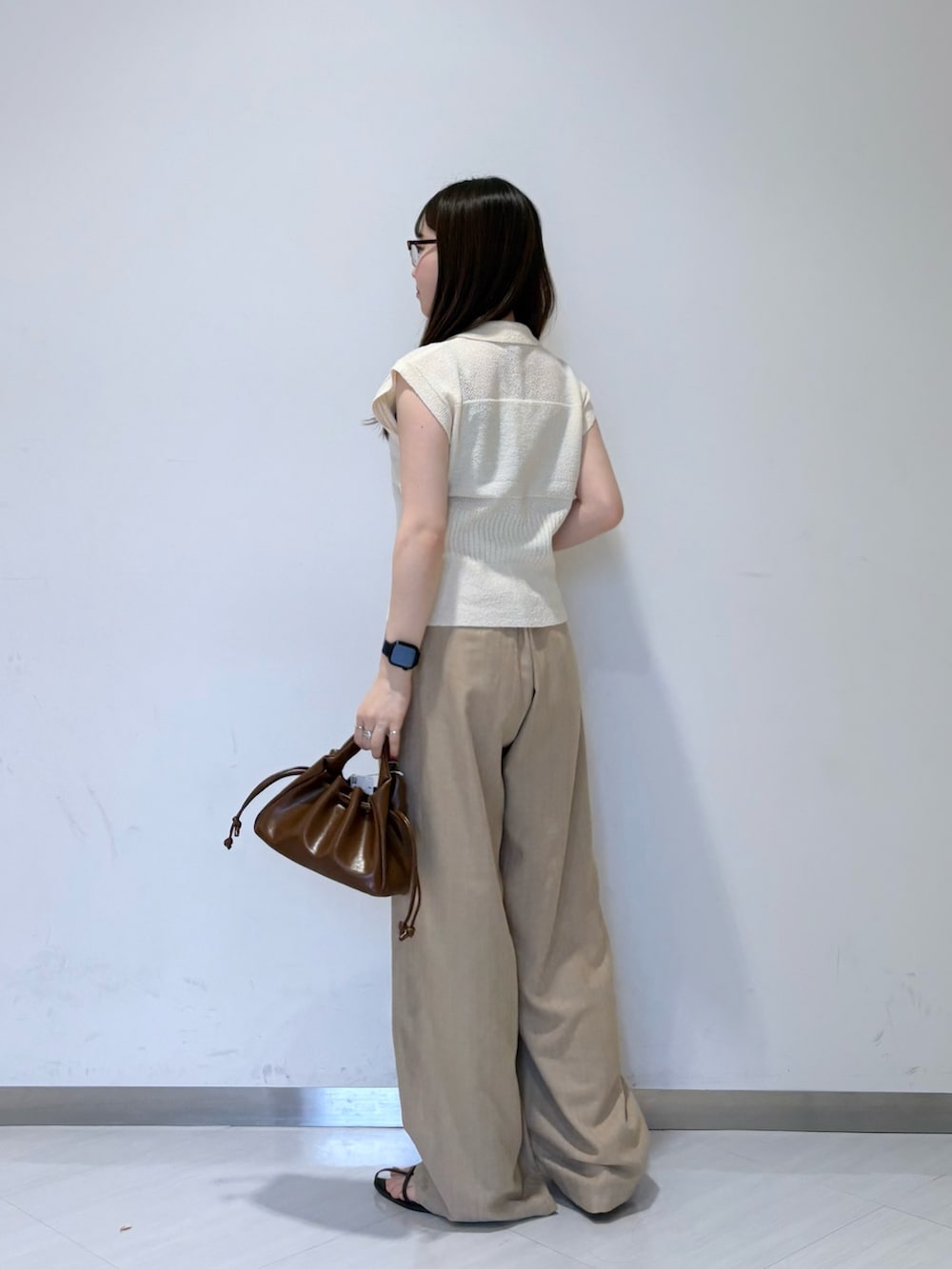 ホワイト系のニット/セーター、ベージュ系のその他パンツ、ブラウン系のハンドバッグを着用したレディースの夏コーディネートの3枚目の写真