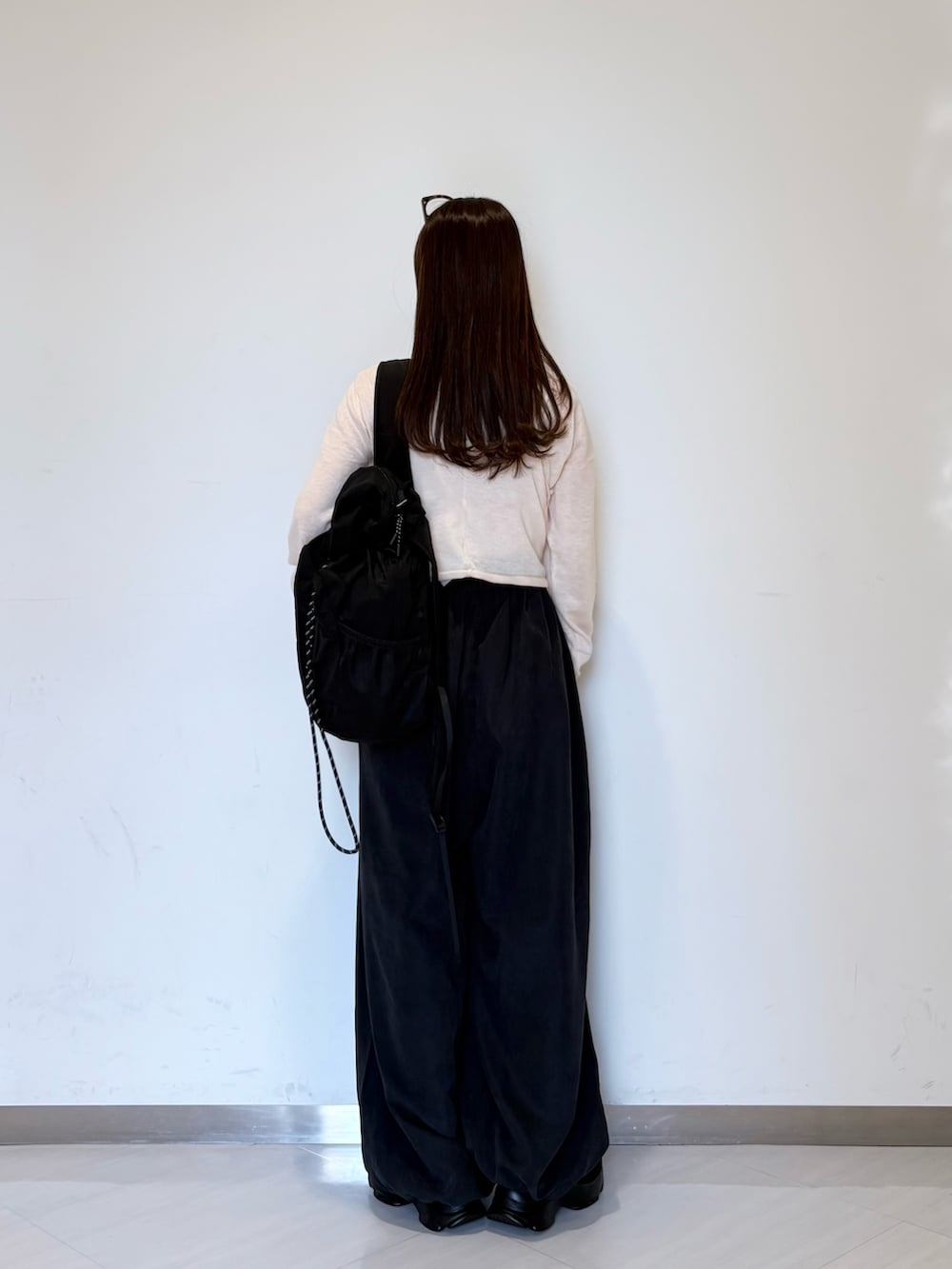 ピンク系のカーディガン/ボレロ、グレー系のその他パンツ、ブラック系のバックパック/リュックを着用したレディースの夏コーディネートの4枚目の写真
