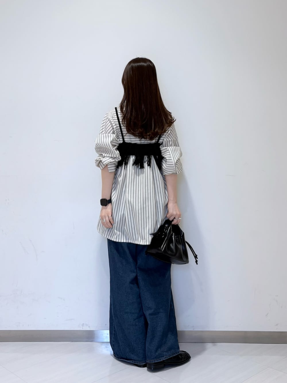 ブラック系のニット/セーター、ブルー系のデニムパンツ、ブラック系のハンドバッグを着用したレディースの夏コーディネートの3枚目の写真