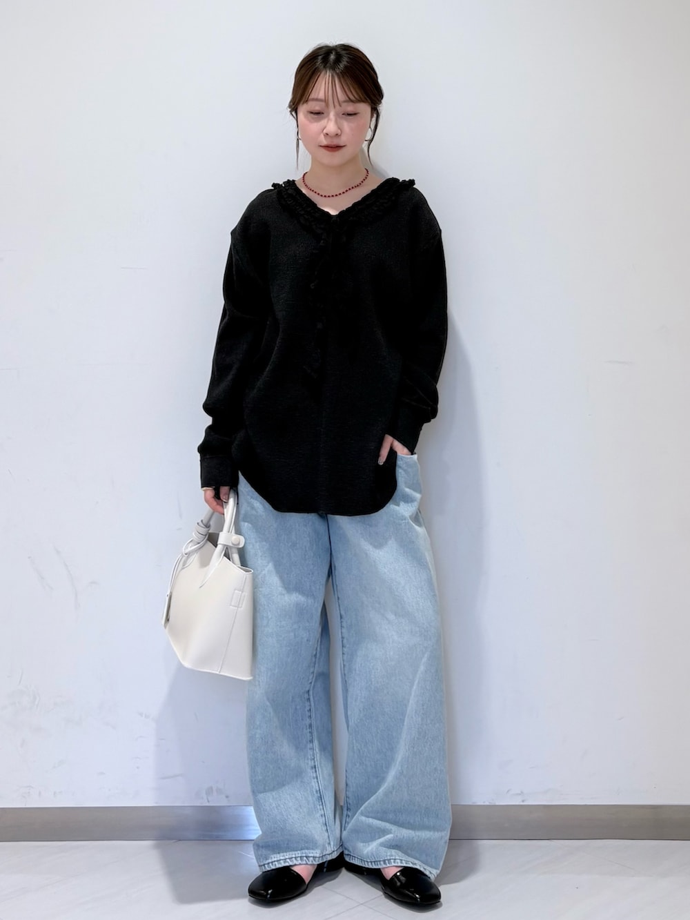 ブラック系のパンプス、ホワイト系のハンドバッグ、ブルー系のデニムパンツを着用したレディースの春コーディネートの4枚目の写真