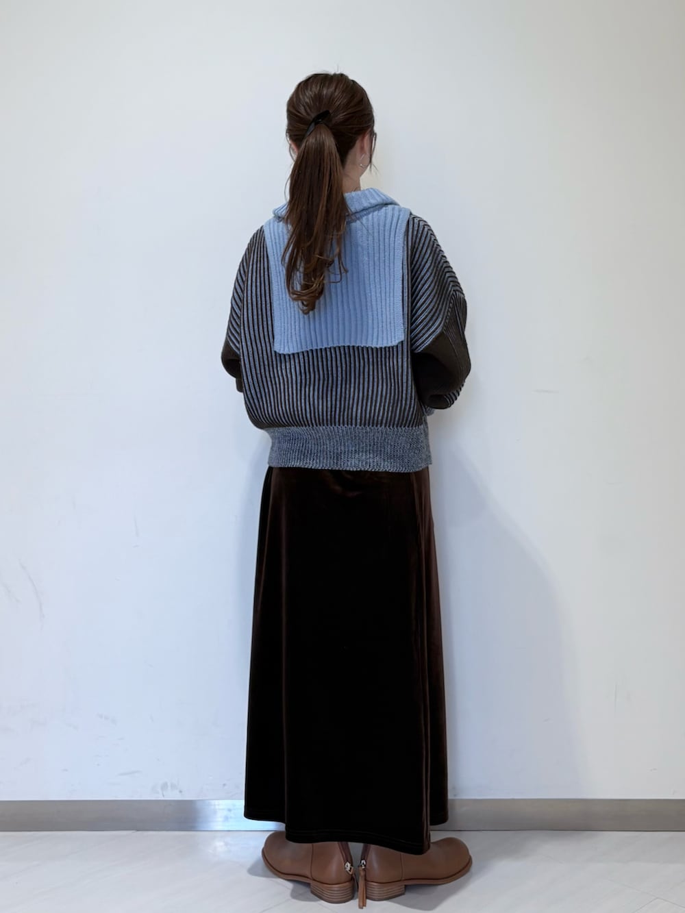 ブルー系のニット/セーター、ブラウン系のスカート、ブラウン系のブーツを着用したレディースの秋コーディネートの3枚目の写真