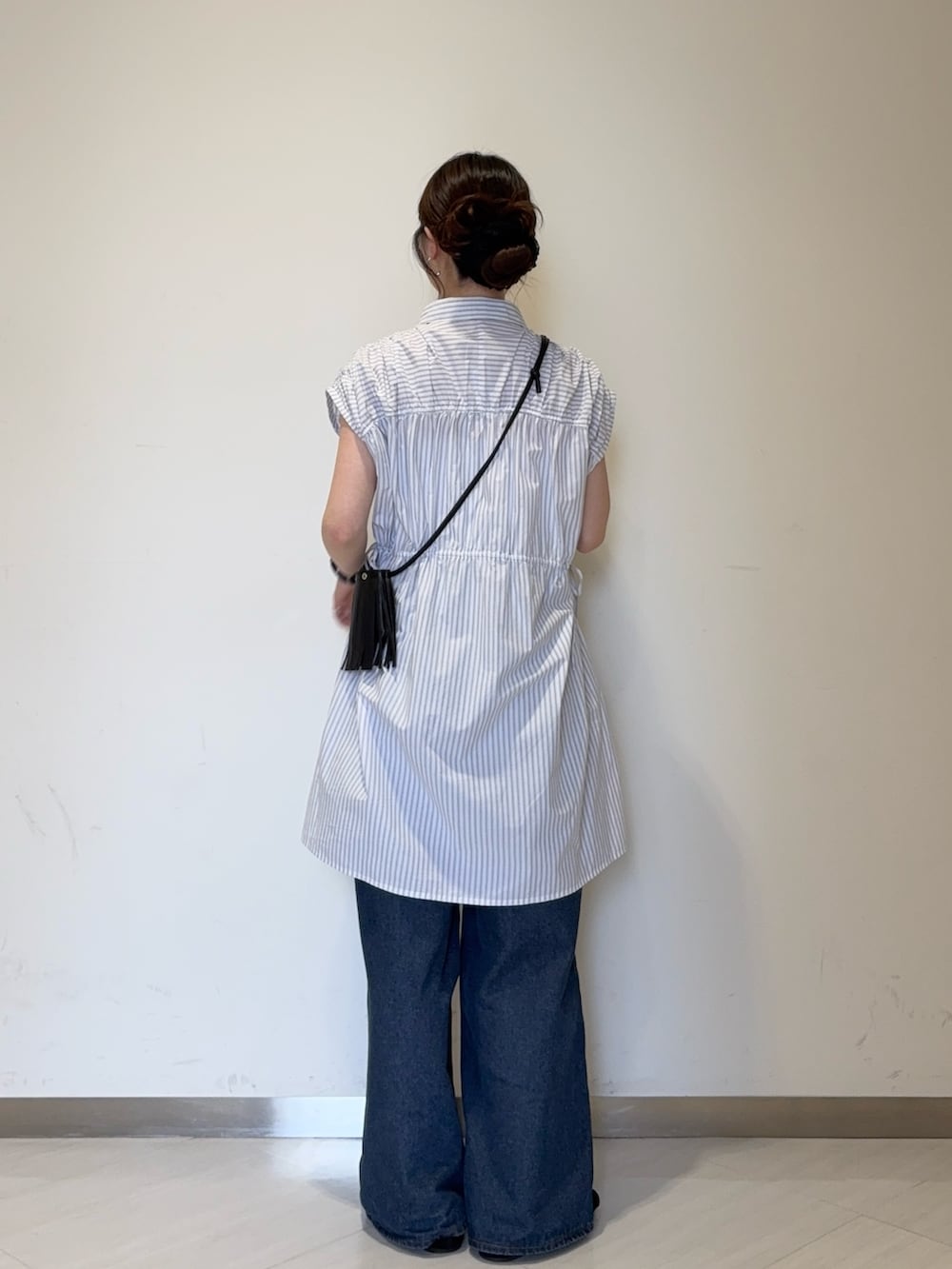 ホワイト系のワンピース、ブルー系のデニムパンツ、ブラック系のサンダルを着用したレディースの夏コーディネートの3枚目の写真