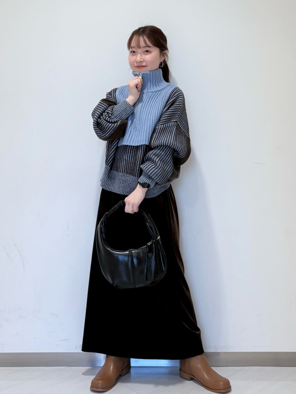 ブルー系のニット/セーター、ブラウン系のスカート、ブラウン系のブーツを着用したレディースの秋コーディネートの2枚目の写真