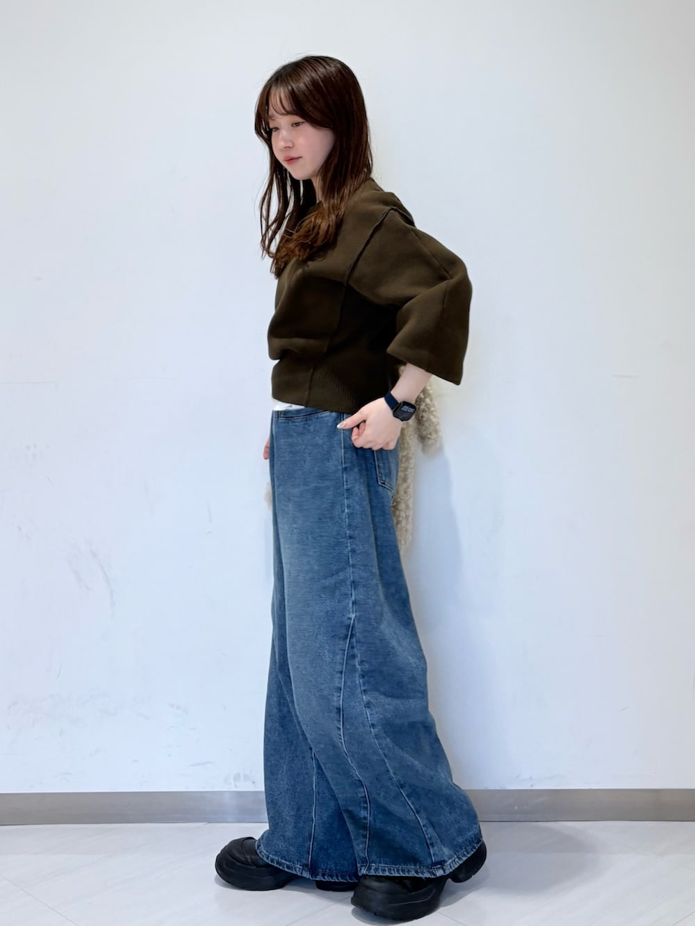 グリーン系のニット/セーター、ホワイト系のTシャツ/カットソー、ブルー系のデニムパンツを着用したレディースの秋コーディネートの2枚目の写真