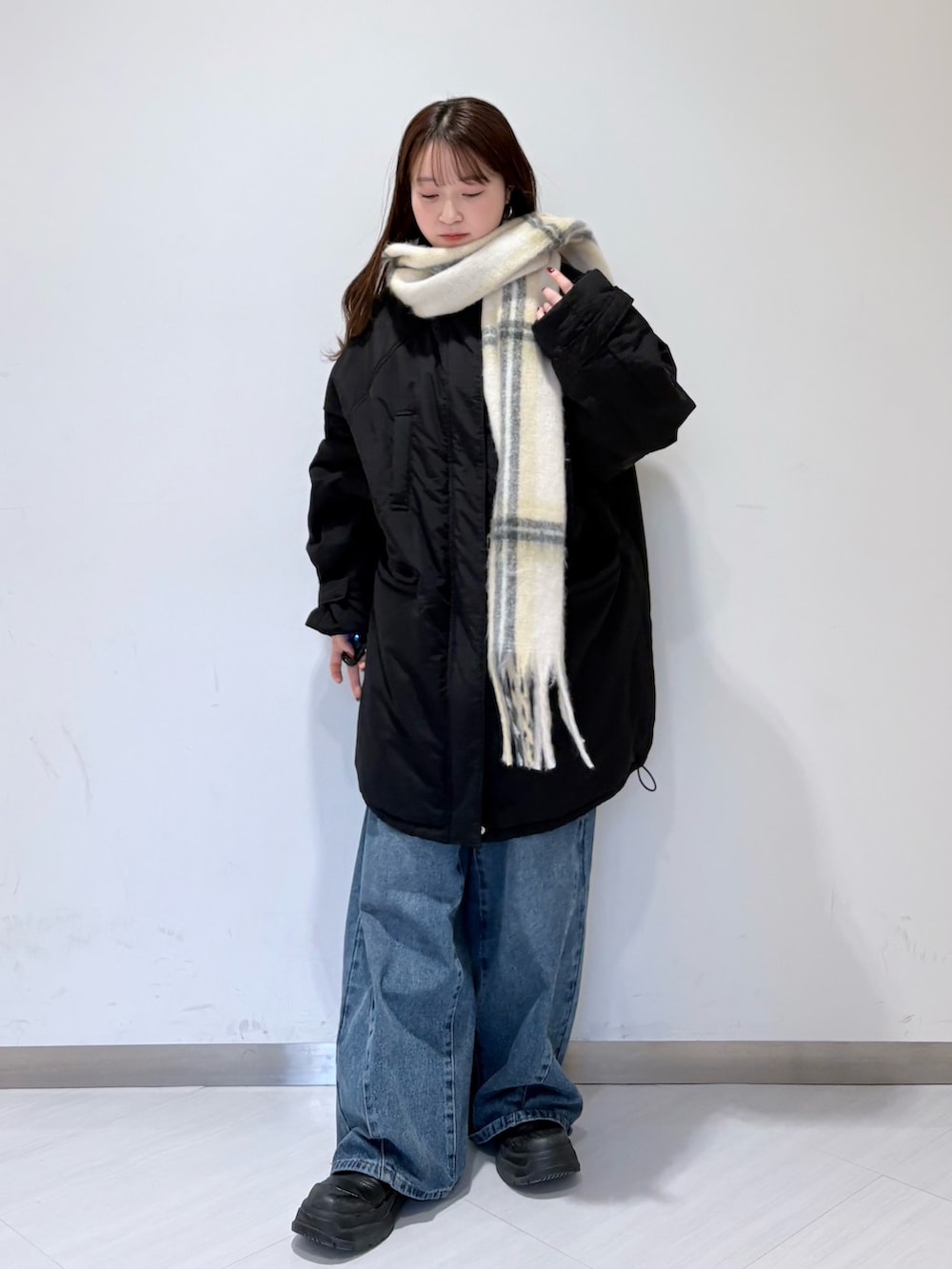 ブラック系のダウンジャケット/コート、ブルー系のデニムパンツ、ホワイト系のストール/ショールを着用したレディースの冬コーディネートの2枚目の写真