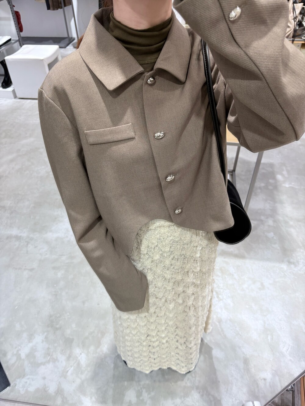ベージュ系のその他アウター、グリーン系のTシャツ/カットソー、ホワイト系のスカートを着用したレディースの秋コーディネートの4枚目の写真
