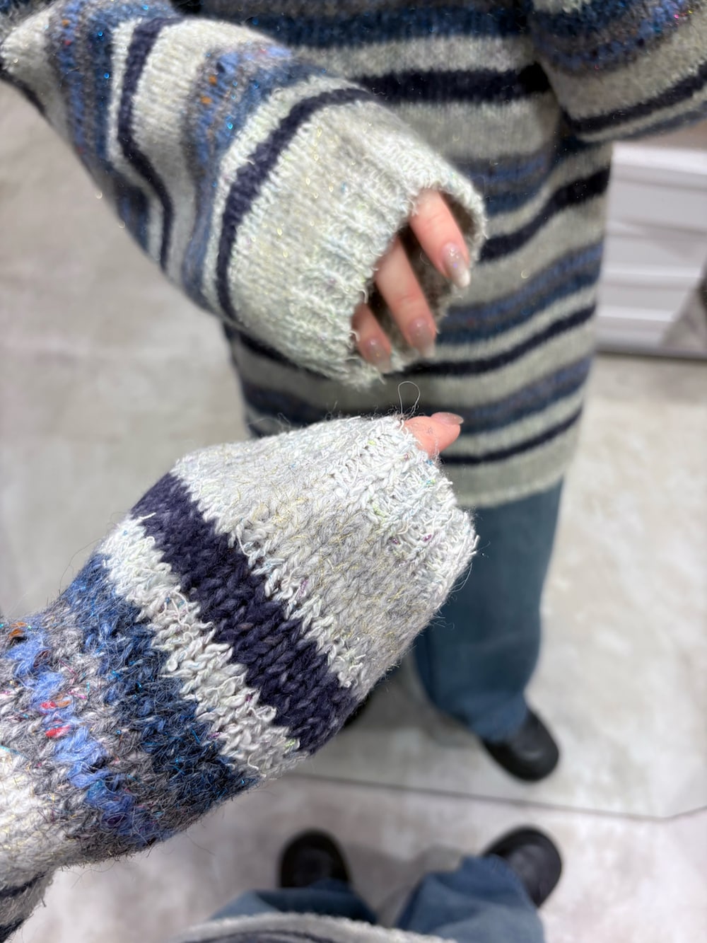 ブルー系のニット/セーター、ブルー系のデニムパンツ、ブラック系のショルダーバッグを着用したレディースの秋コーディネートの4枚目の写真