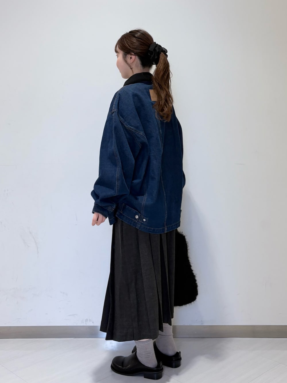 グレー系のニット/セーター、グレー系のスカート、ブラック系のその他シューズを着用したレディースの秋コーディネートの5枚目の写真