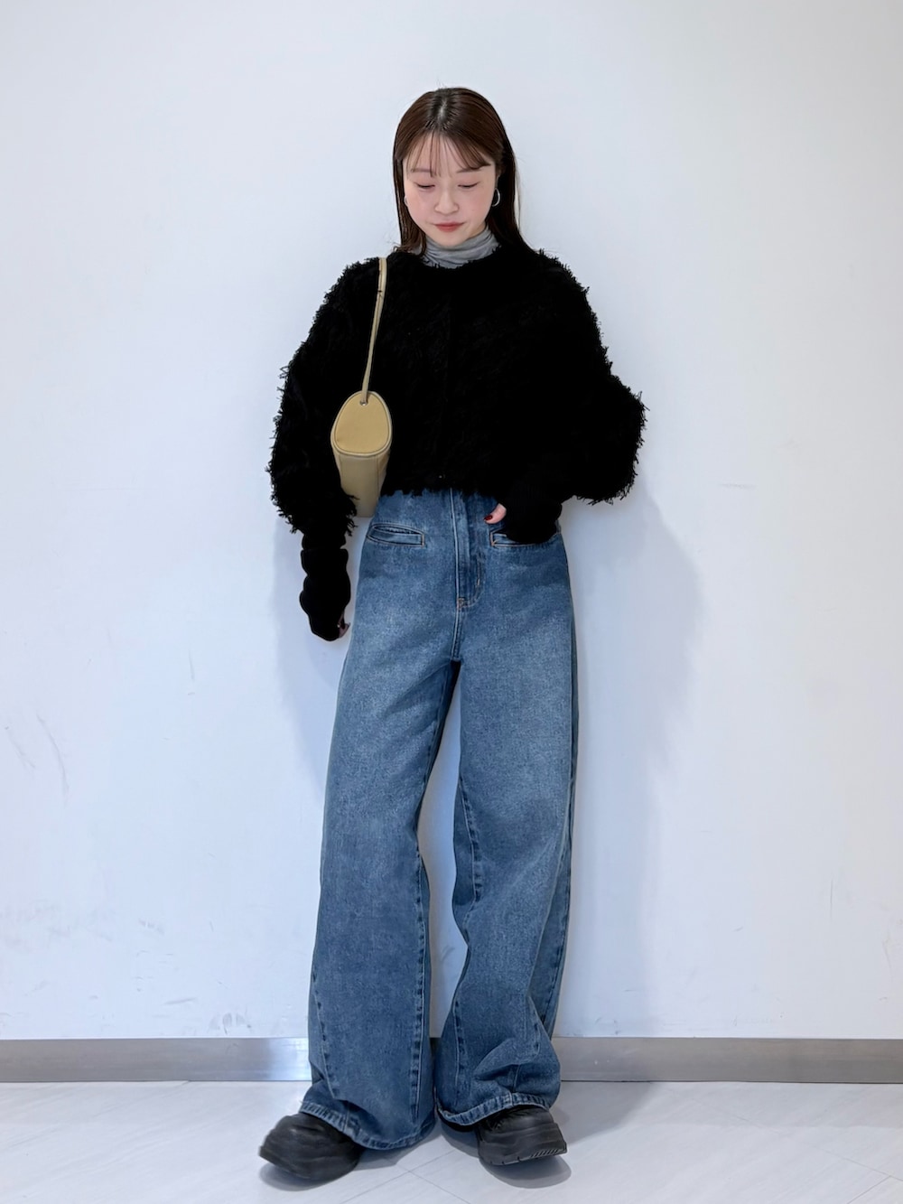 ブラック系のカーディガン/ボレロ、グレー系のTシャツ/カットソー、ブルー系のデニムパンツを着用したレディースの冬コーディネートの4枚目の写真