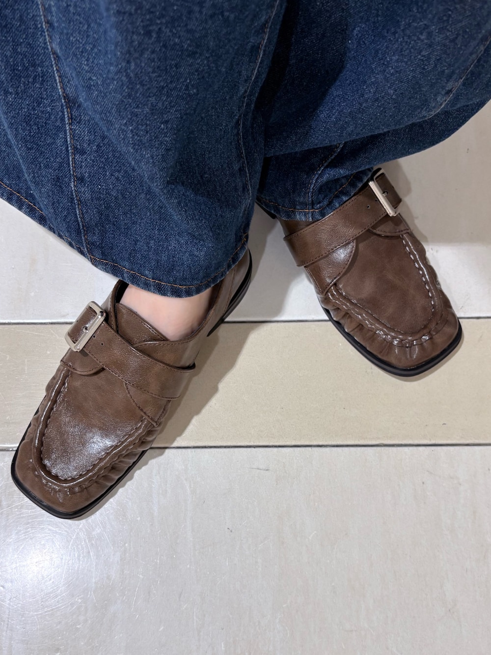 ブラウン系のローファー、ブルー系のデニムパンツ、ブラウン系のハンドバッグを着用したレディースの夏コーディネートの4枚目の写真