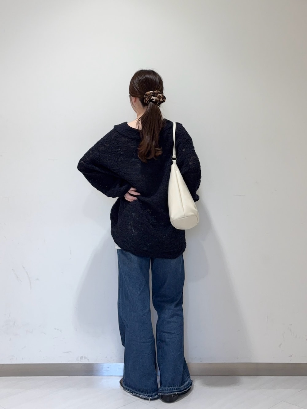 ブルー系のデニムパンツ、ブラウン系のローファー、ホワイト系のショルダーバッグを着用したレディースの秋コーディネートの3枚目の写真