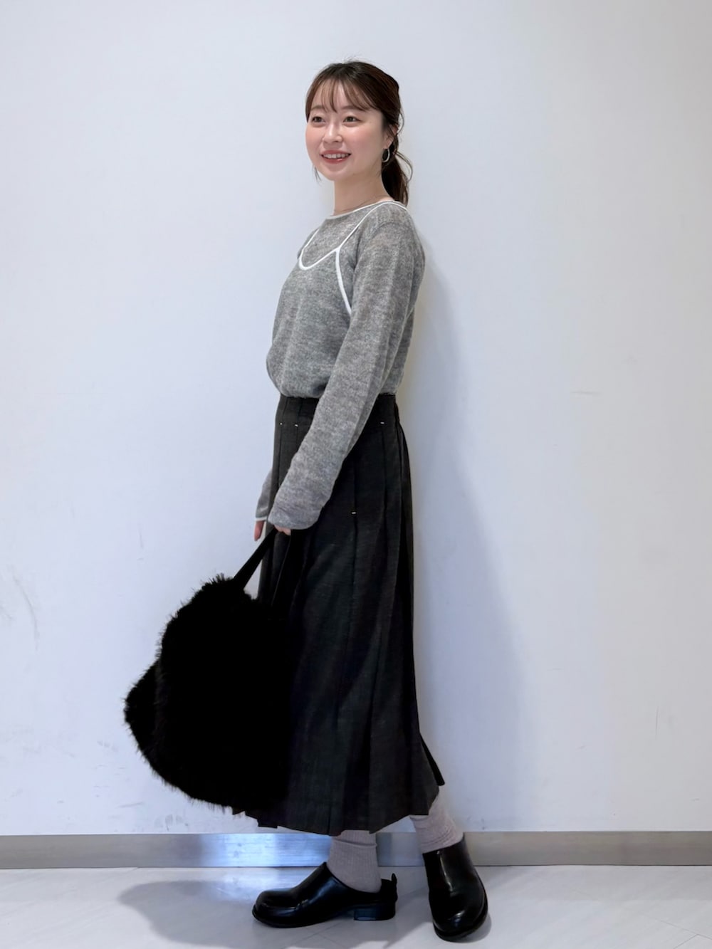 グレー系のニット/セーター、グレー系のスカート、ブラック系のその他シューズを着用したレディースの秋コーディネートの2枚目の写真