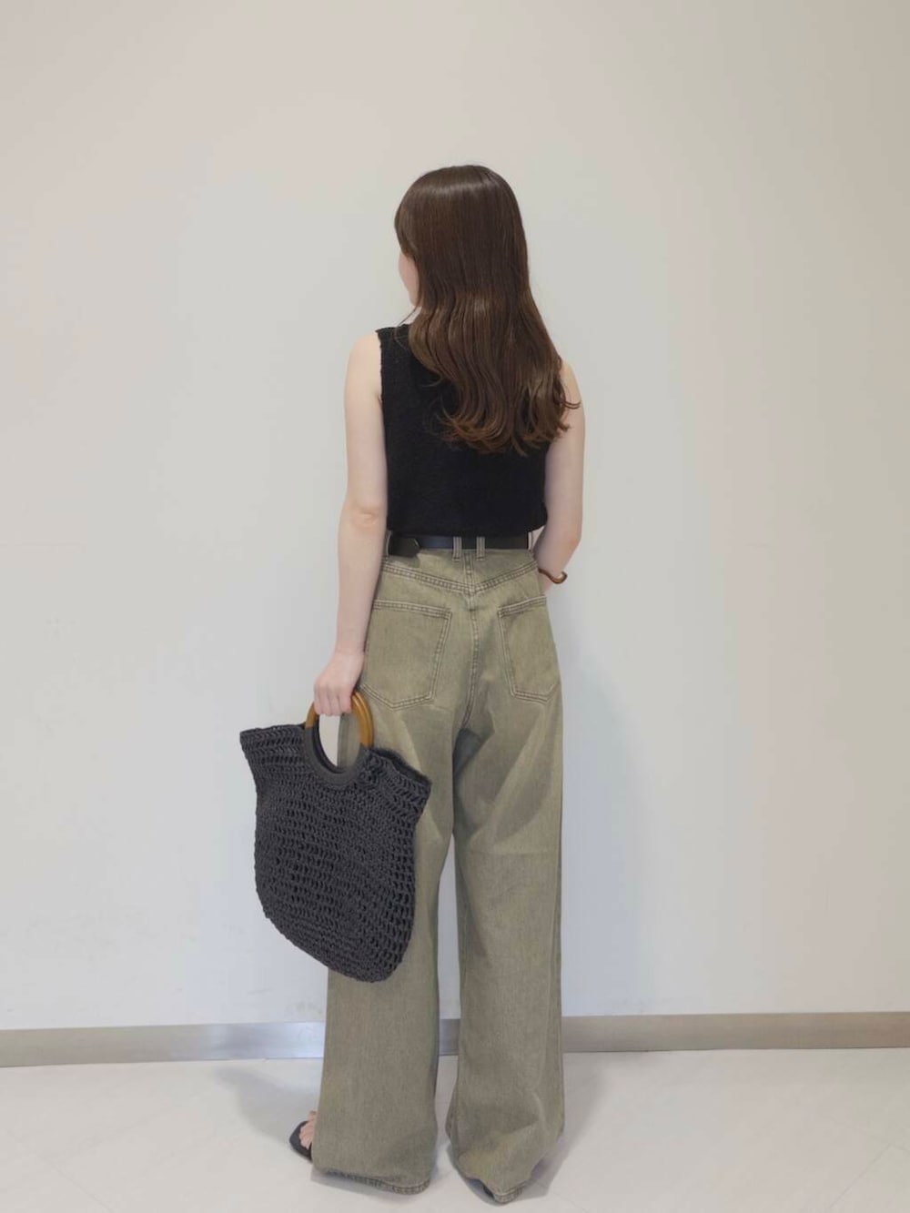 ブラック系のトートバッグ、ブラック系のサンダル、グリーン系のデニムパンツを着用したレディースの夏コーディネートの2枚目の写真