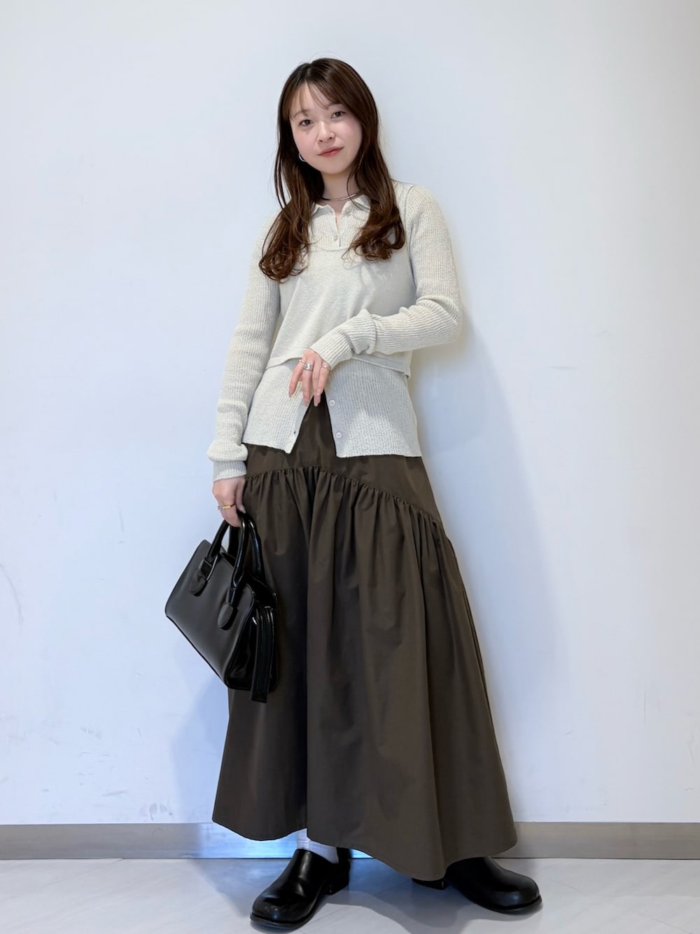 ブラック系のその他シューズ、ブラック系のボストンバッグ、グリーン系のスカートを着用したレディースの冬コーディネートの2枚目の写真