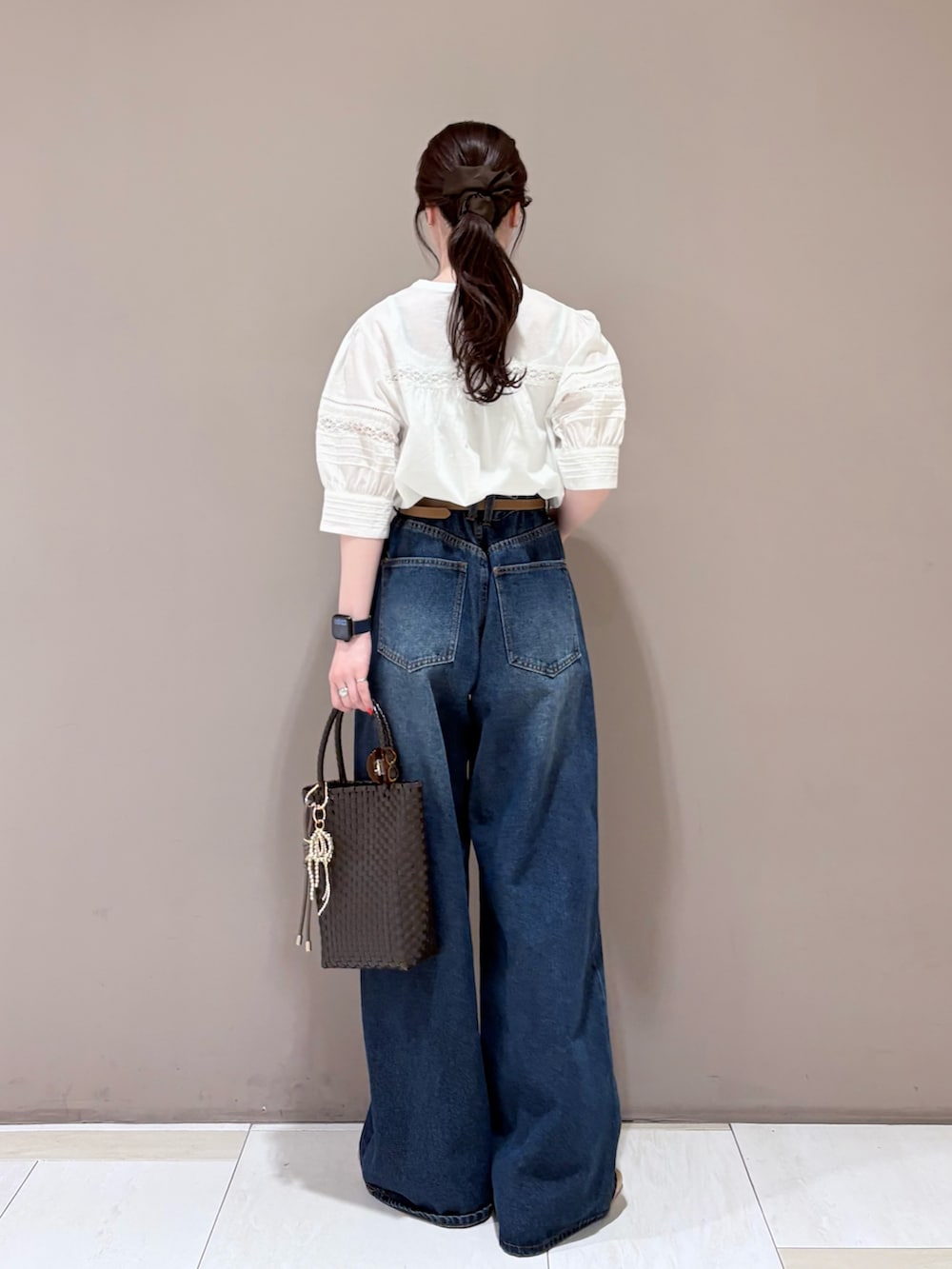 イエロー系のパンプス、ブラウン系のトートバッグ、ブルー系のデニムパンツを着用したレディースの春コーディネートの3枚目の写真