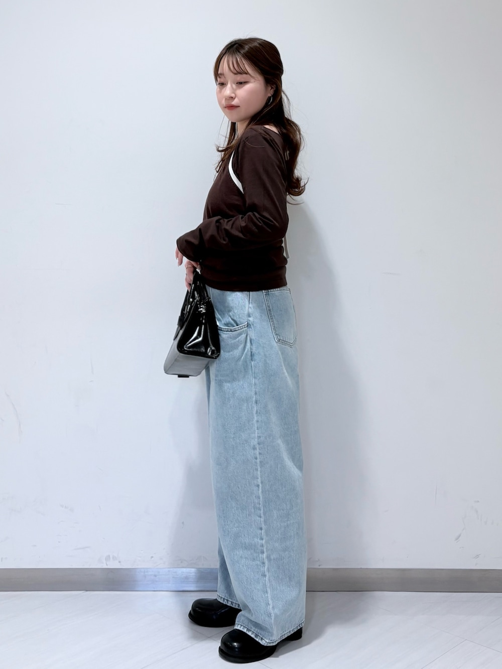 ブラウン系のTシャツ/カットソー、ブルー系のデニムパンツ、ブラック系のボストンバッグを着用したレディースの春コーディネートの2枚目の写真