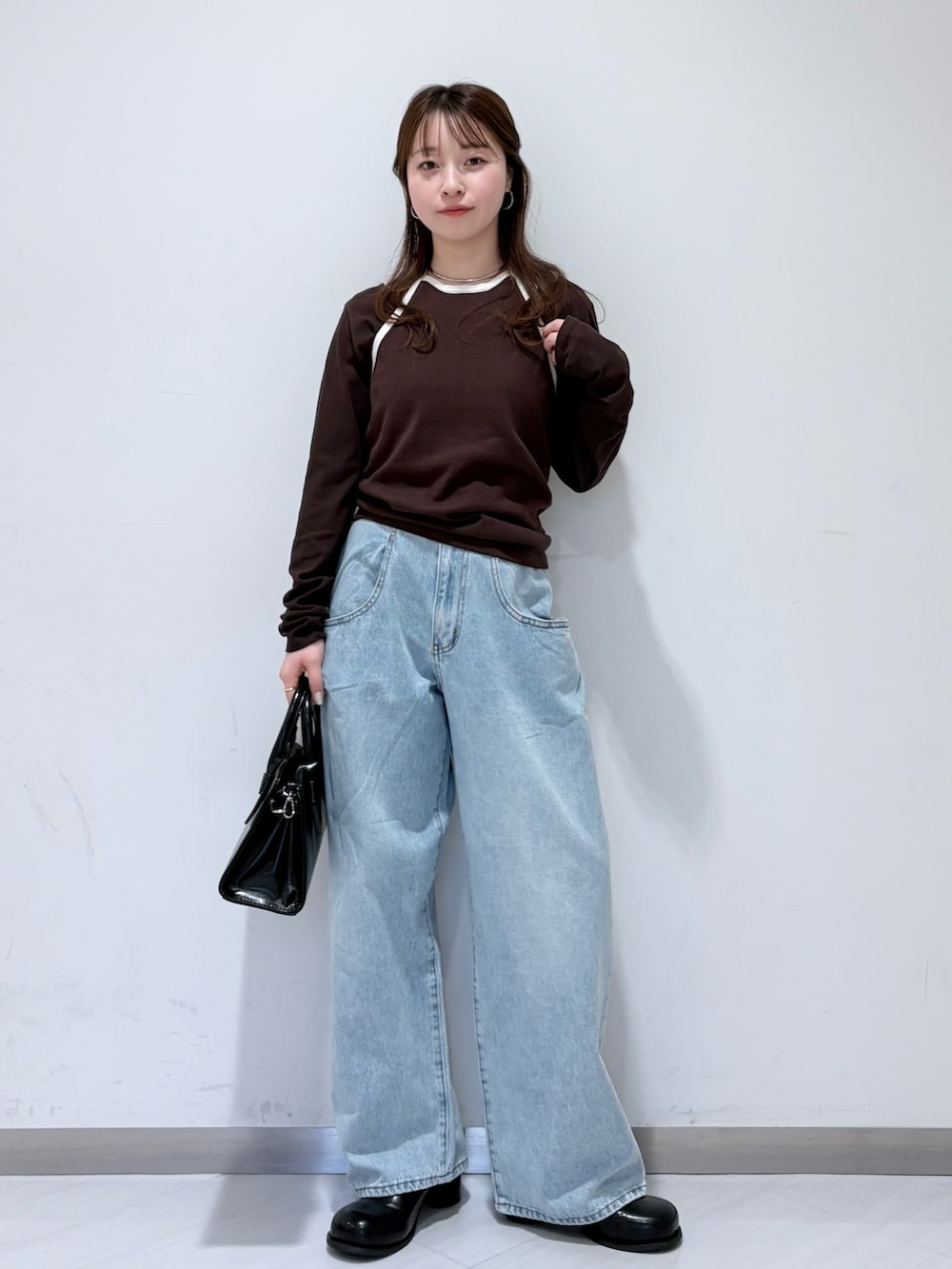 ブラウン系のTシャツ/カットソー、ブルー系のデニムパンツ、ブラック系のボストンバッグを着用したレディースの春コーディネートの4枚目の写真