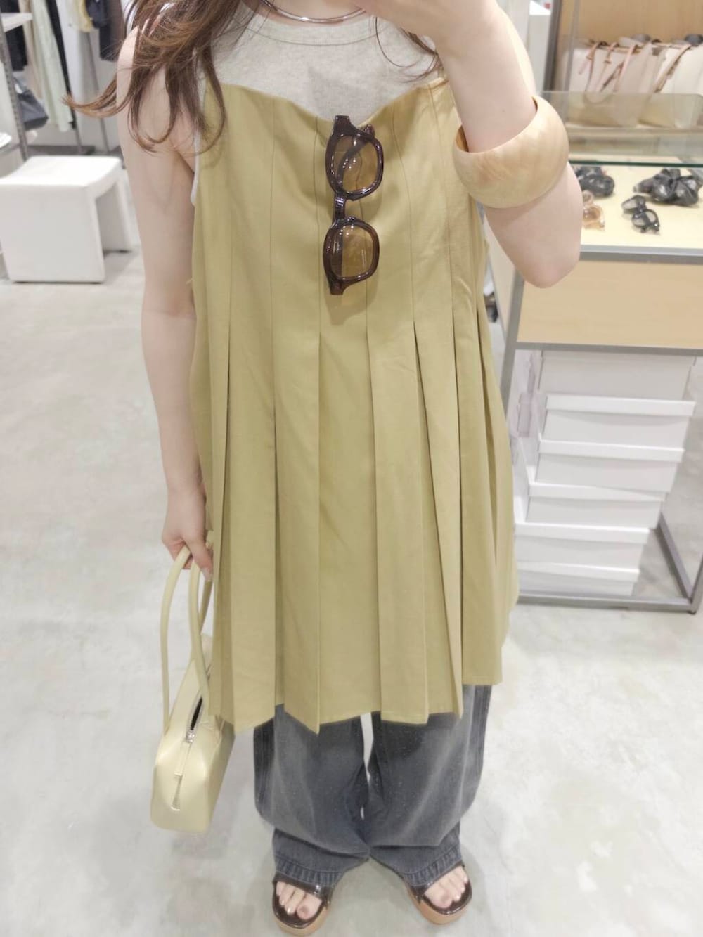 ベージュ系のタンクトップ、イエロー系のショルダーバッグ、ブラック系のデニムパンツを着用したレディースの夏コーディネートの3枚目の写真