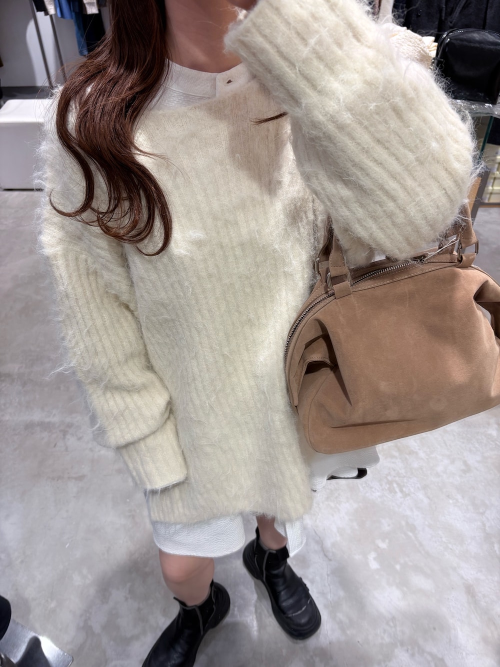 ホワイト系のニット/セーター、ベージュ系のボストンバッグ、ホワイト系のシャツ/ブラウスを着用したレディースの冬コーディネートの4枚目の写真