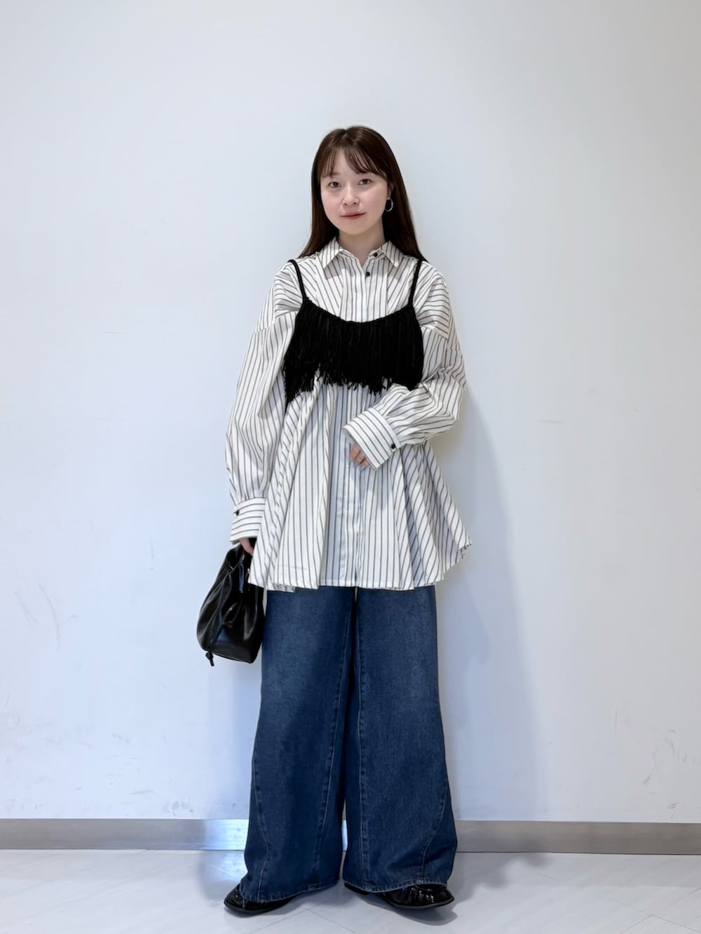 ブラック系のニット/セーター、ブルー系のデニムパンツ、ブラック系のハンドバッグを着用したレディースの夏コーディネートの4枚目の写真