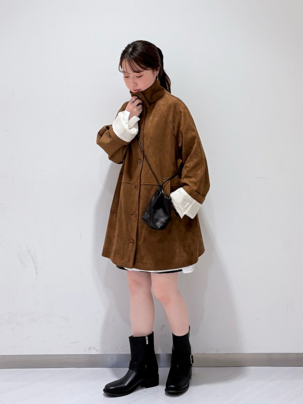 ブラック系のブーツ、ブラック系のショルダーバッグ、ホワイト系のシャツ/ブラウスを着用したレディースの秋コーディネートの4枚目の写真