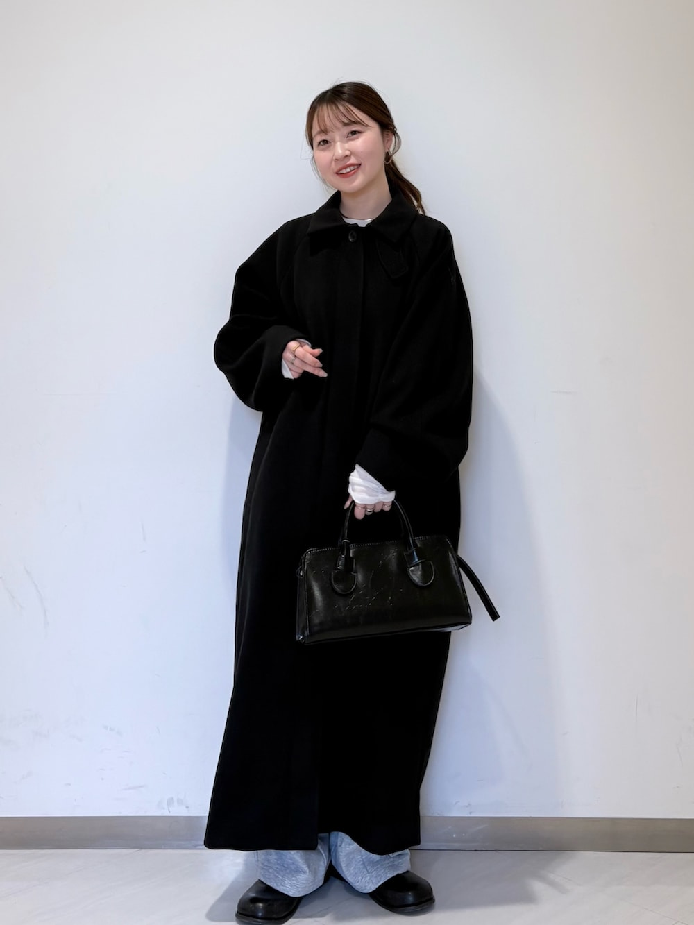 ブラック系のステンカラーコート、グレー系のTシャツ/カットソー、ブラック系のその他シューズを着用したレディースの冬コーディネートの3枚目の写真