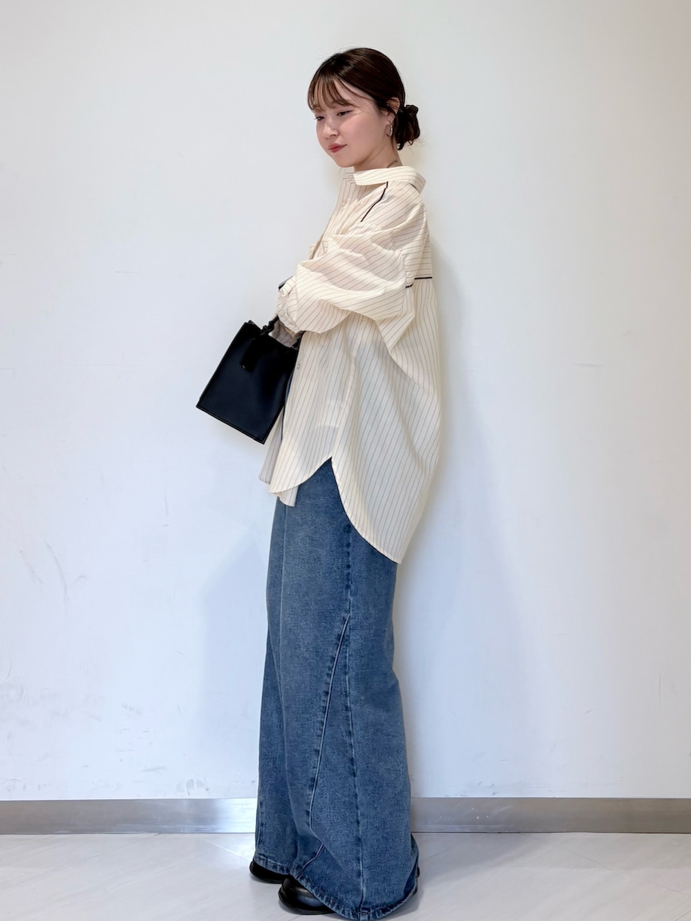 ブルー系のデニムパンツ、ブラック系のハンドバッグ、ホワイト系のキャミソールを着用したレディースの春コーディネートの2枚目の写真