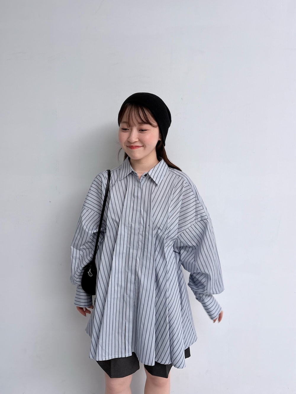 ブルー系のチュニック、グレー系のその他パンツ、ブラック系のショルダーバッグを着用したレディースの夏コーディネートの4枚目の写真