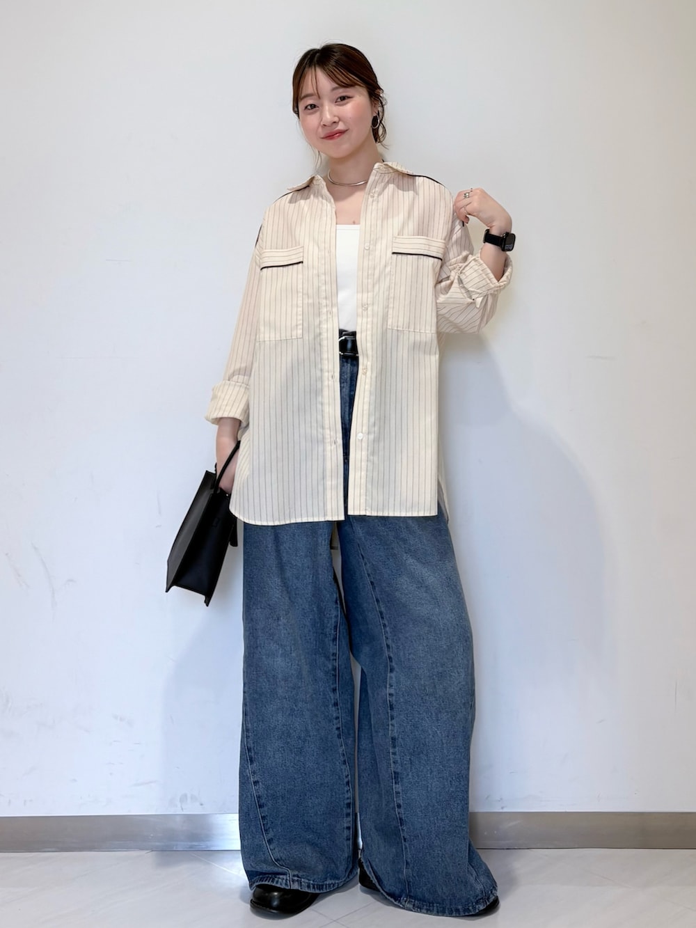 ブルー系のデニムパンツ、ブラック系のハンドバッグ、ホワイト系のキャミソールを着用したレディースの春コーディネートの4枚目の写真