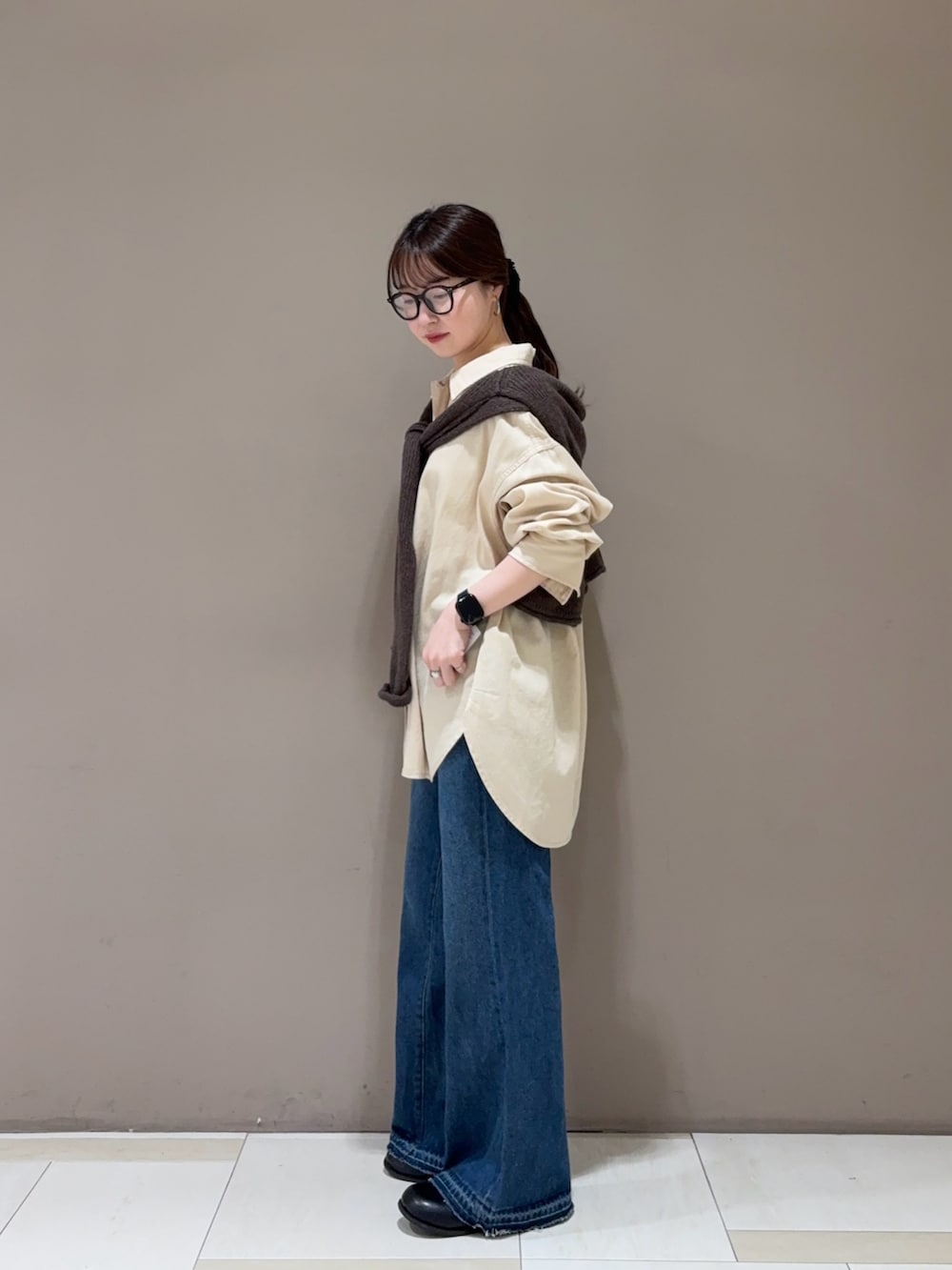 ブルー系のデニムパンツ、ベージュ系のシャツ/ブラウス、ブラウン系のニット/セーターを着用したレディースの秋コーディネートの3枚目の写真