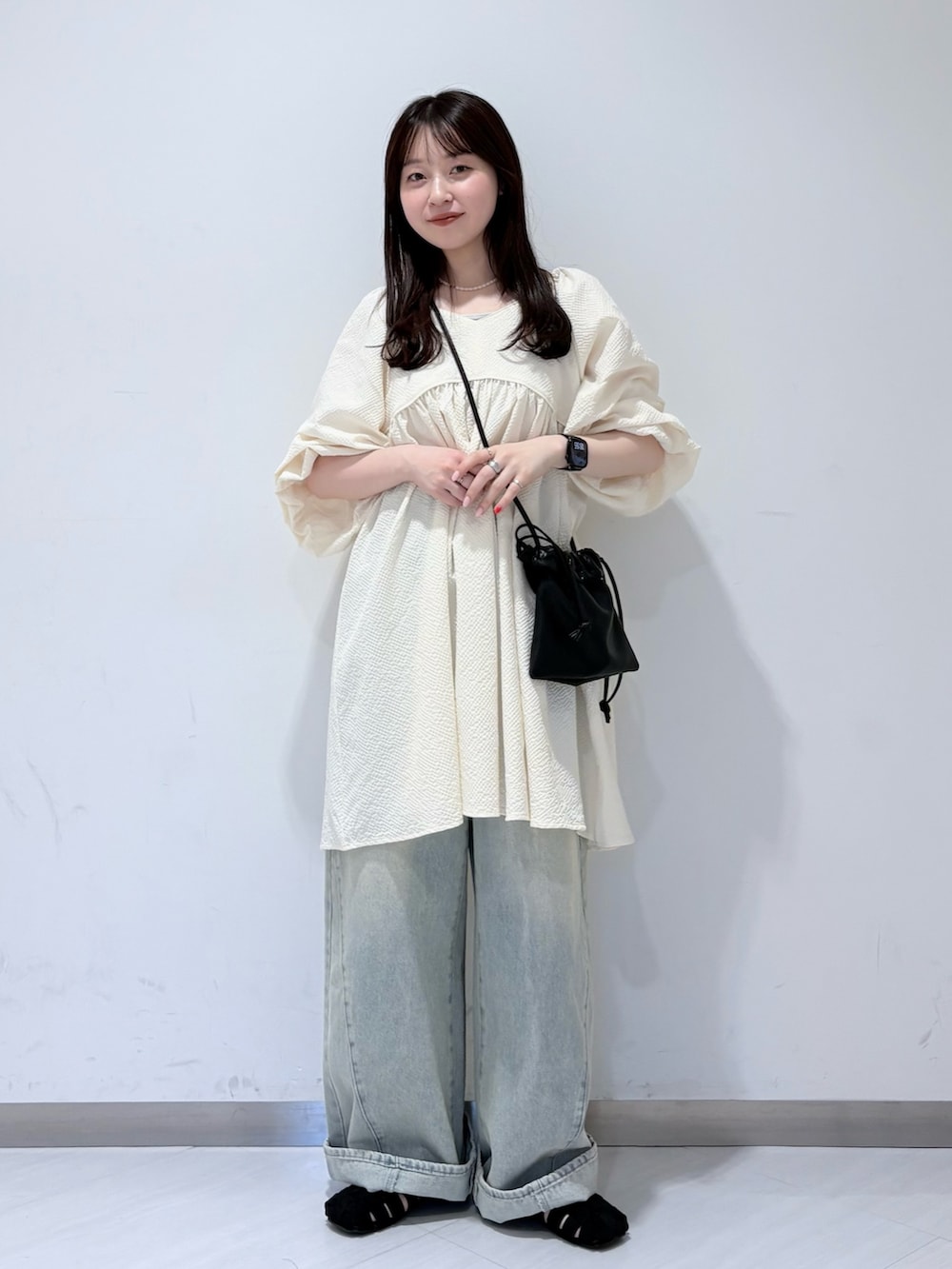 ホワイト系のワンピース、ブルー系のデニムパンツ、ブラック系のサンダルを着用したレディースの春コーディネートの4枚目の写真