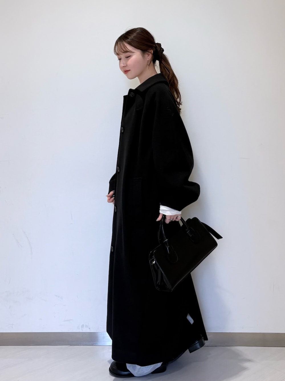 ブラック系のステンカラーコート、グレー系のTシャツ/カットソー、ブラック系のその他シューズを着用したレディースの冬コーディネートの2枚目の写真