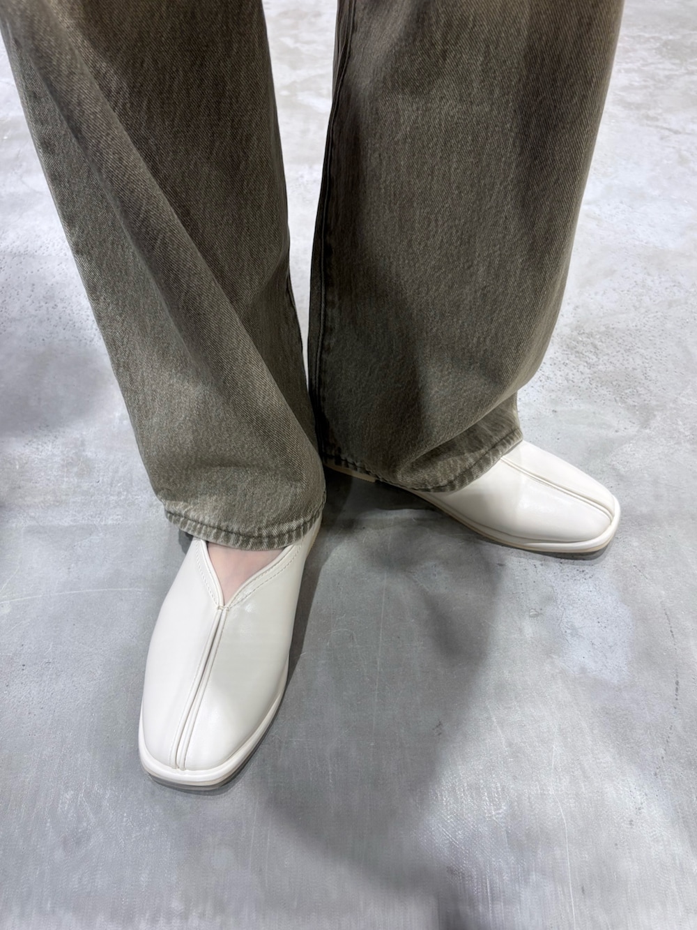 ホワイト系のパンプス、グリーン系のデニムパンツ、ブラウン系のボストンバッグを着用したレディースの冬コーディネートの4枚目の写真