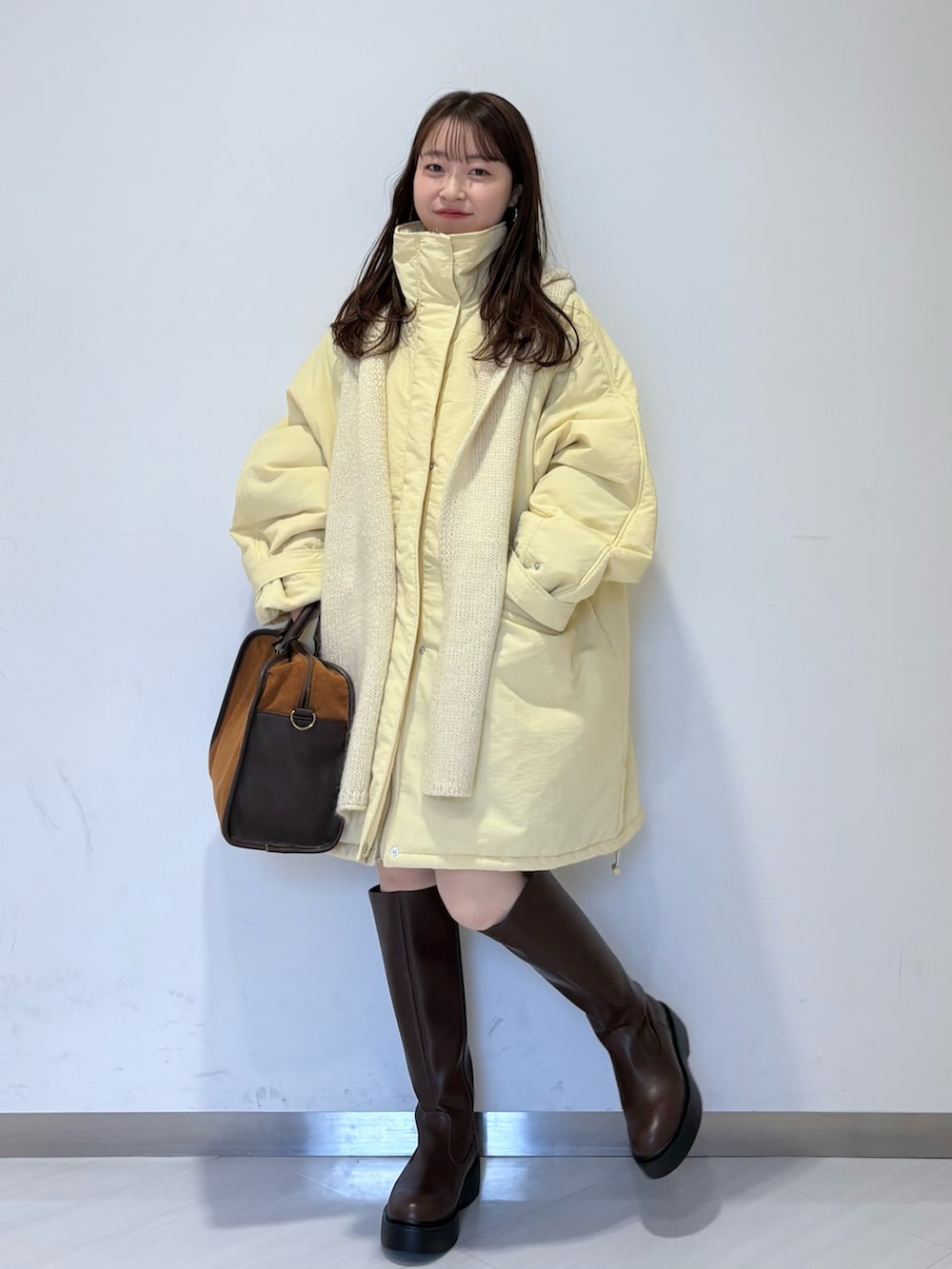 イエロー系のダウンジャケット/コート、イエロー系のボストンバッグ、ブラウン系のブーツを着用したレディースの秋コーディネートの3枚目の写真