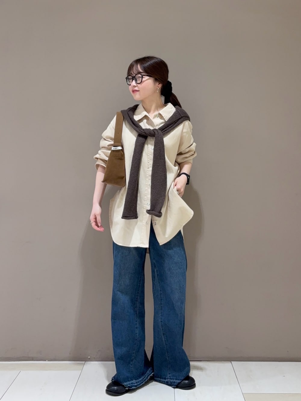 ブルー系のデニムパンツ、ベージュ系のシャツ/ブラウス、ブラウン系のニット/セーターを着用したレディースの秋コーディネートの5枚目の写真