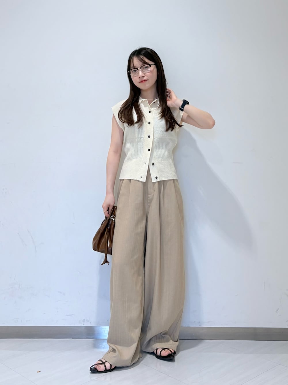 ホワイト系のニット/セーター、ベージュ系のその他パンツ、ブラウン系のハンドバッグを着用したレディースの夏コーディネートの5枚目の写真
