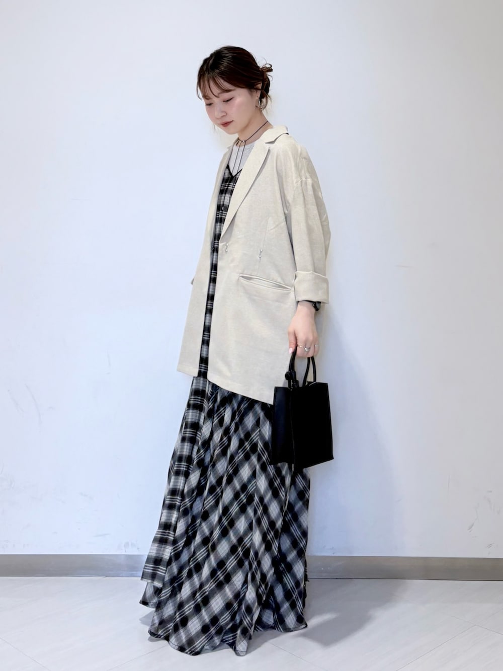 ベージュ系のタンクトップ、ブラック系のワンピース、ブラック系のハンドバッグを着用したレディースの春コーディネートの2枚目の写真