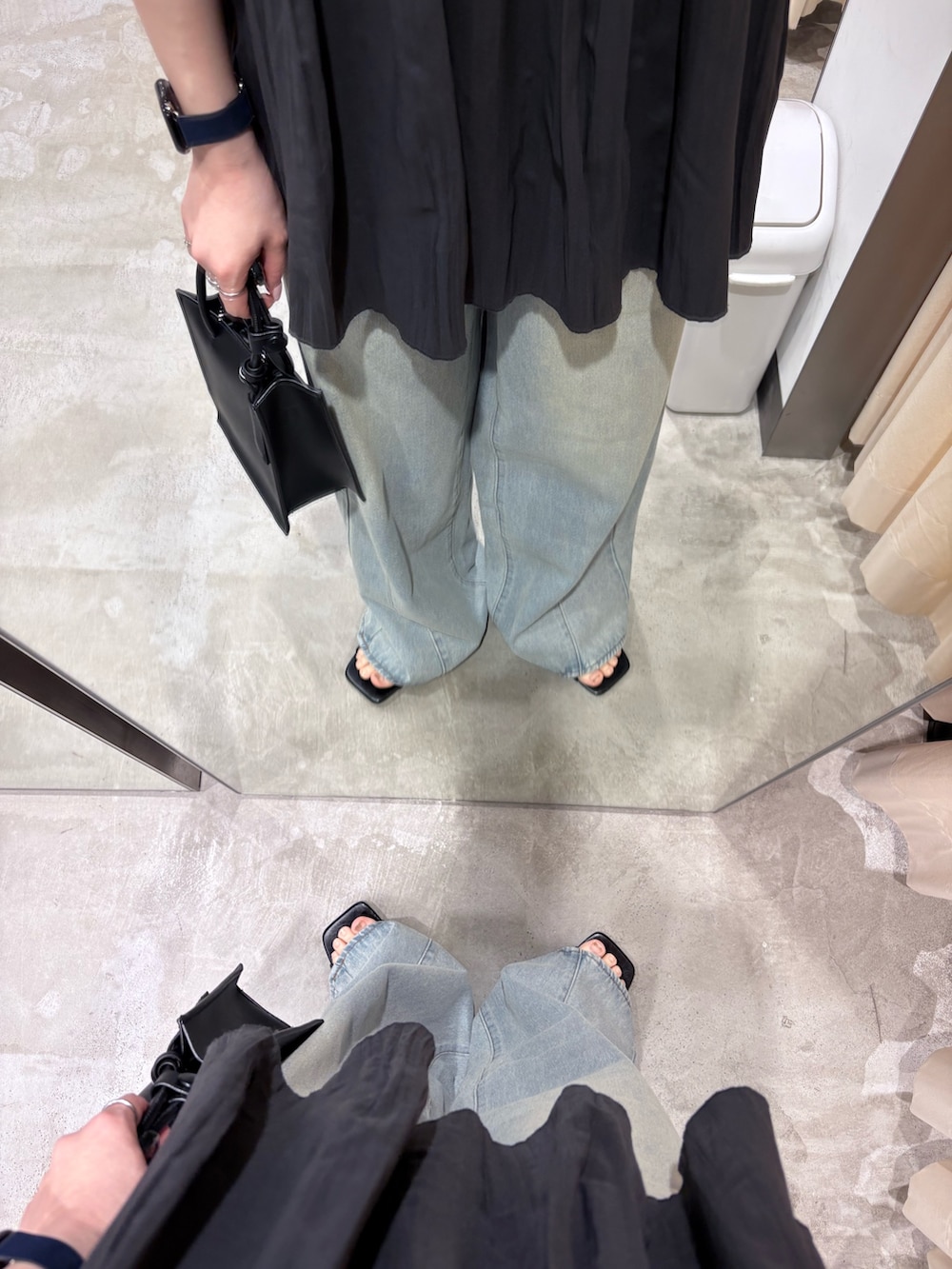 ブラック系のサンダル、ホワイト系のハンドバッグ、ブルー系のデニムパンツを着用したレディースの春コーディネートの5枚目の写真