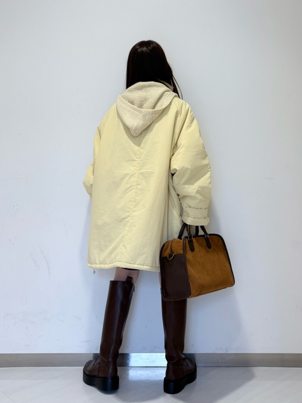 イエロー系のダウンジャケット/コート、イエロー系のボストンバッグ、ブラウン系のブーツを着用したレディースの秋コーディネートの2枚目の写真