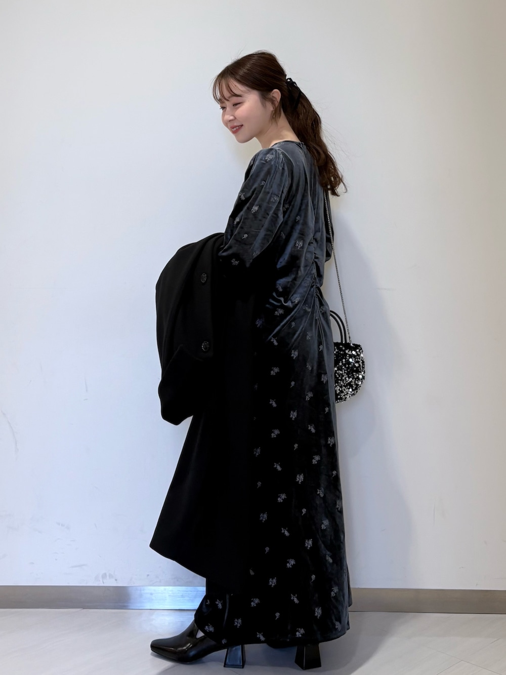 グレー系のワンピース、ブラック系のステンカラーコート、ブラック系のパンプスを着用したレディースの冬コーディネートの3枚目の写真