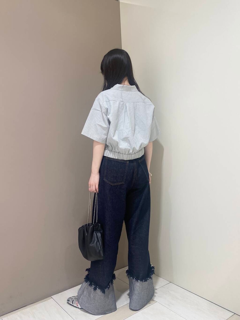 ブラック系のハンドバッグ、シルバー系のサンダル、ブルー系のデニムパンツを着用したレディースの春コーディネートの2枚目の写真