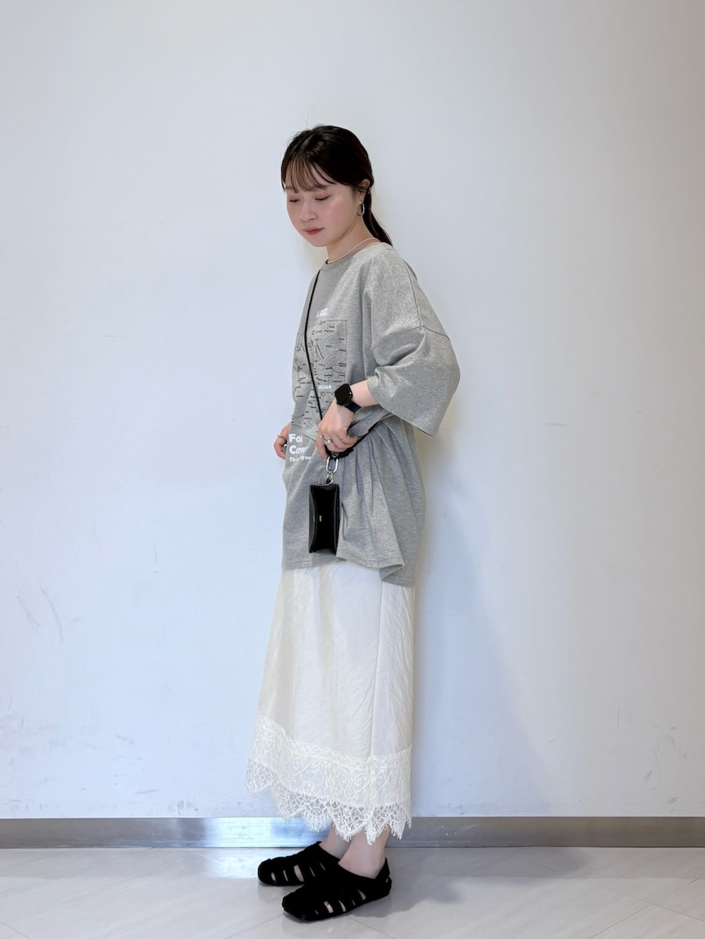 グレー系のTシャツ/カットソー、ホワイト系のスカート、ブラック系のサンダルを着用したレディースの夏コーディネートの2枚目の写真