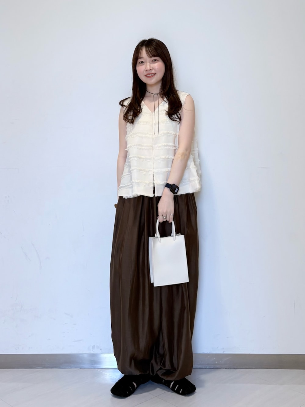 ホワイト系のベスト、ブラウン系のその他パンツ、ホワイト系のハンドバッグを着用したレディースの春コーディネートの4枚目の写真