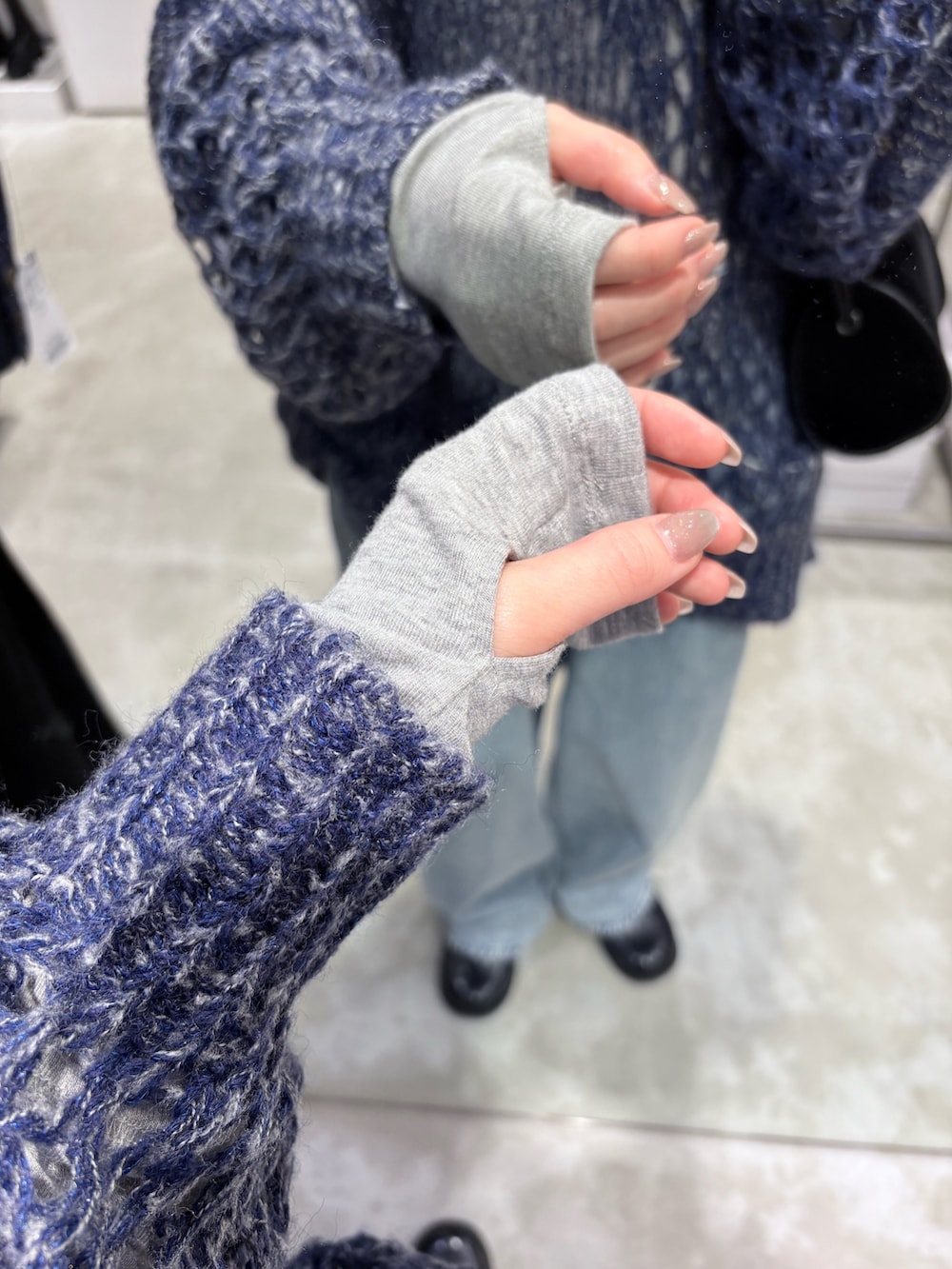 ブルー系のニット/セーター、グレー系のTシャツ/カットソー、ブルー系のデニムパンツを着用したレディースの秋コーディネートの5枚目の写真