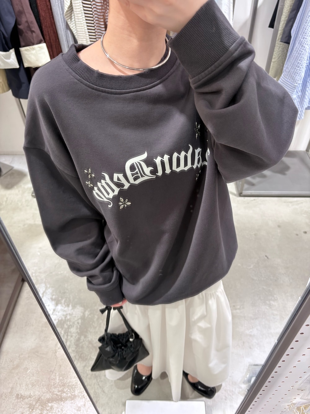 グレー系のスウェット、ブラック系のローファー、ホワイト系のスカートを着用したレディースの春コーディネートの4枚目の写真