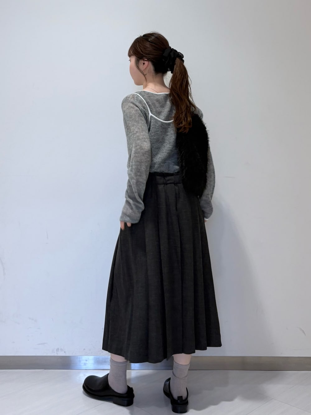 グレー系のニット/セーター、グレー系のスカート、ブラック系のその他シューズを着用したレディースの秋コーディネートの3枚目の写真